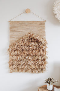 Full of organic texture this piece is a perfect mix of both coastal and neutral bohemian elements & is inspired by tropical resort style living. The seagrass weaved backing hangs from a timber rod & has been woven and sewn by hand using a mix of jute & natural alang alang grass. Layers of raffia follow to form the thick & textured layers of fringing that create a texture that will transform your space to a tropical oasis.